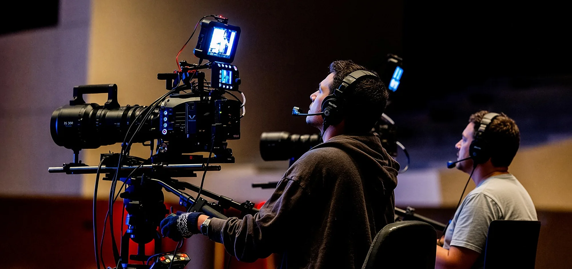 Two camera operators with headsets running a cinema camera on a studio rig