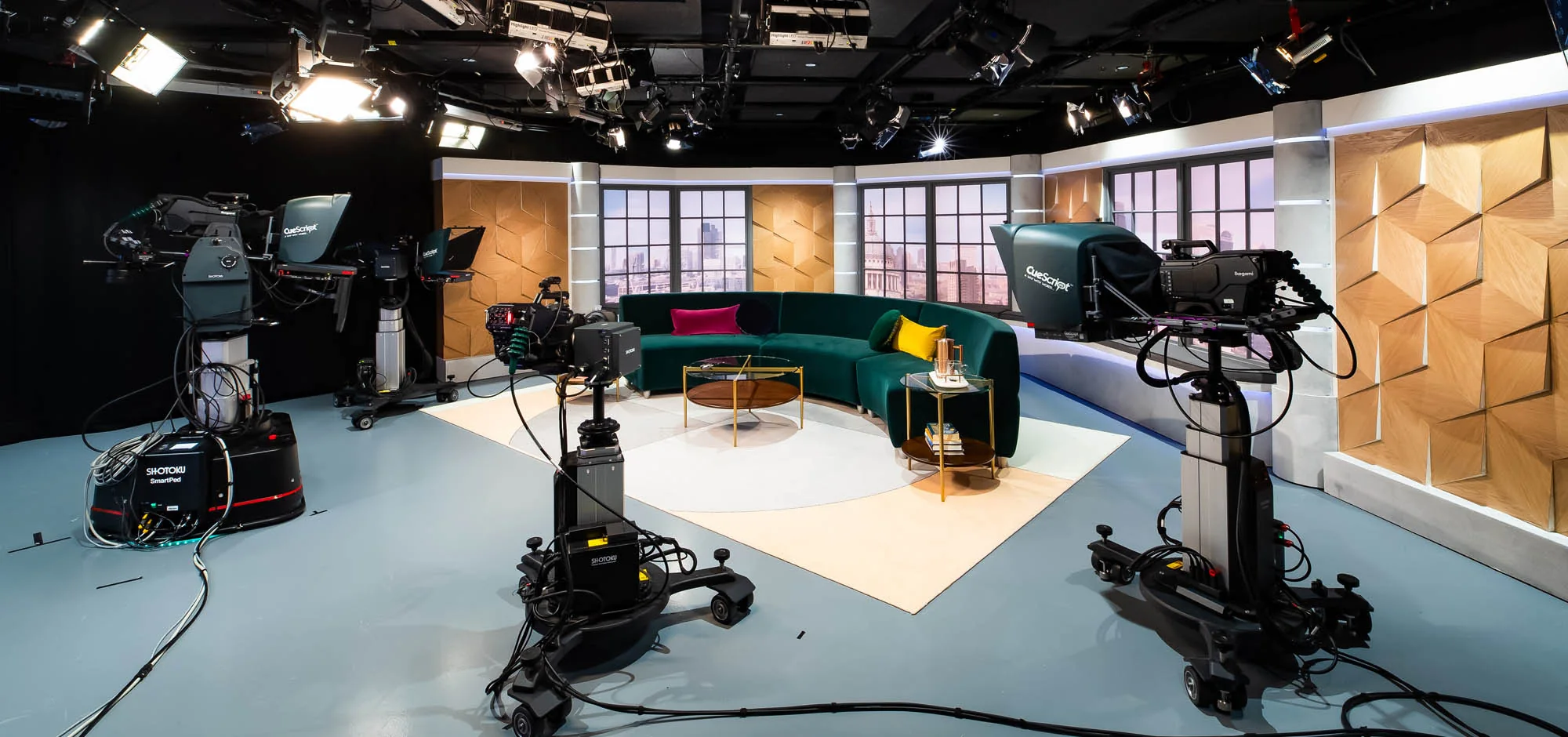 Television studio with pedestal cameras, teleprompters and a full lighting grid