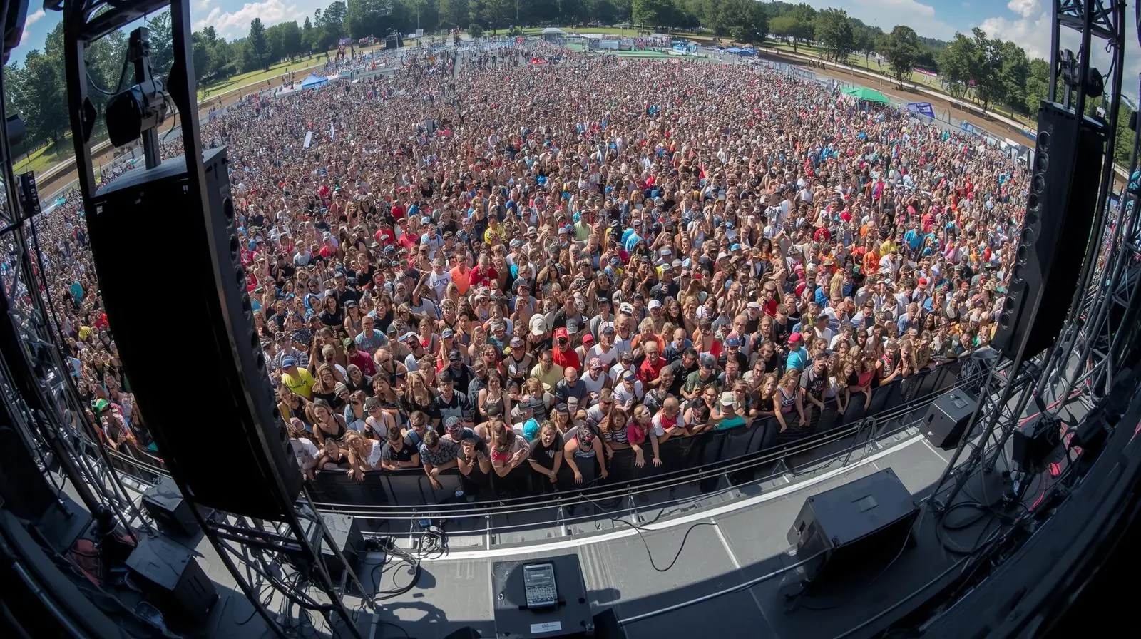 Large outdoor audience where speakers are clearly visible on stands or trusses